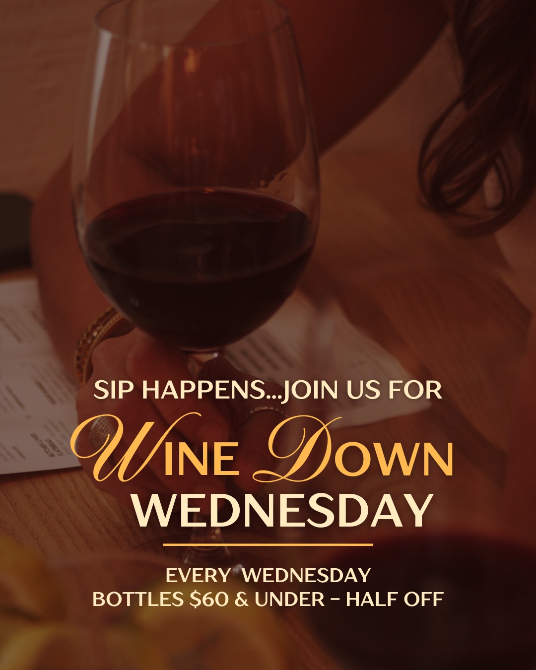 Close-up of a glass of red wine on a table with menu, promoting Wine Down Wednesday with bottles $60 and under half off